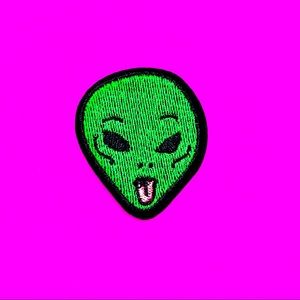 Green alien sticking out tongue iron on patch